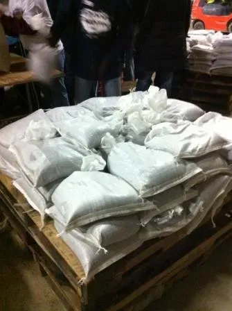 A skid of sandbags, with 3 levels of bags piled on it, approximately 12 per row