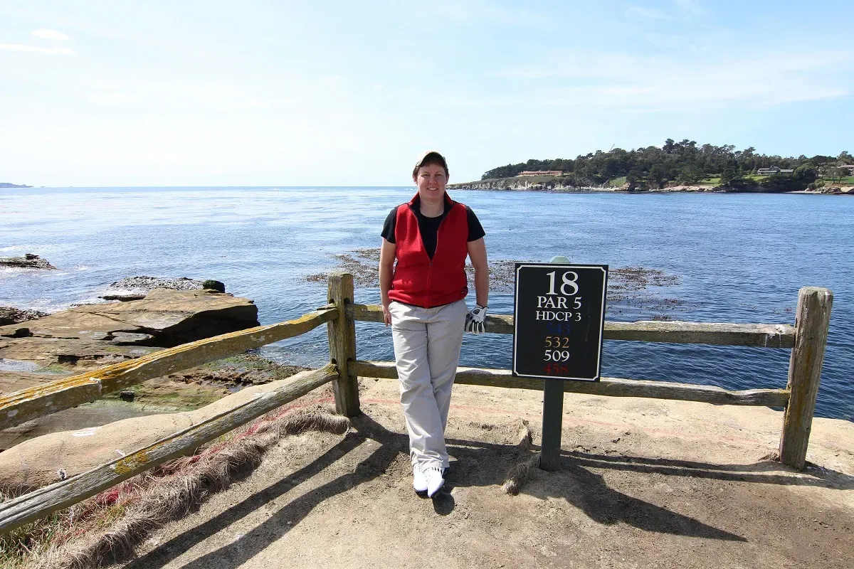 A picture of me leaning against the Pebble Beach 18th hole sign.