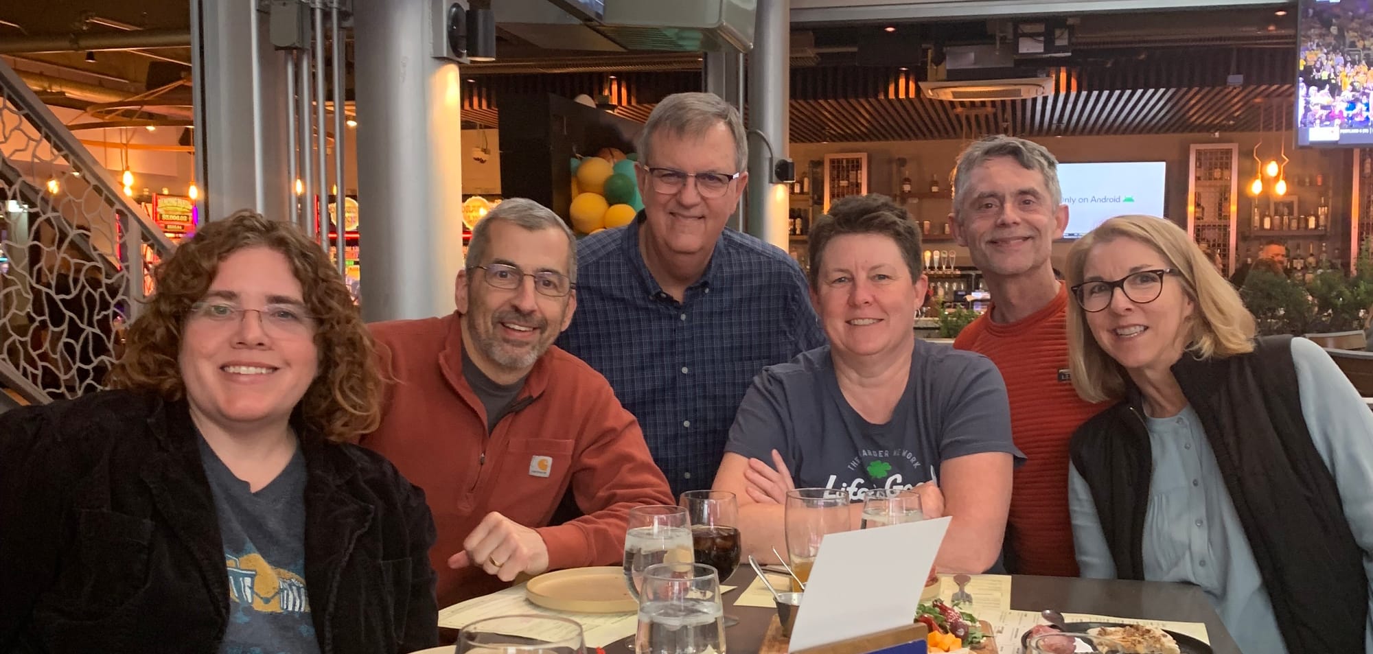 6 of the #SML gang at dinner, left to right: Christina Lanham with brown curly hair and glasses, wearing a grey t-shirt under a black jacket; Bob Kundrat, short grey hair and glasses, wearing a red half zip sweater; Jack Irby, short grey hair and glasses wearing a blue checked button down shirt, me with short brown hair wearing a blue t-shirt; Greg Kramer, short grey hair wearing a red t-shirt; Sheila Hart, blonde hair and glasses wearing a blue shirt under a black vest.