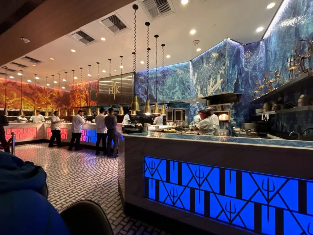 Hell's Kitchen Las Vegas restaurant interior showing open kitchen with red and blue themed walls and staff in white uniforms.
