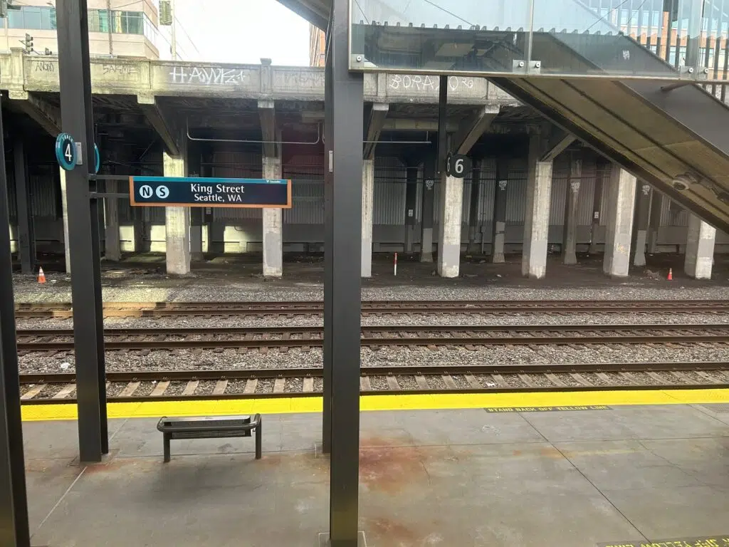 Train platform at King Street Station, Seattle, showing Track 4 sign, bench, yellow safety line, and railroad tracks.