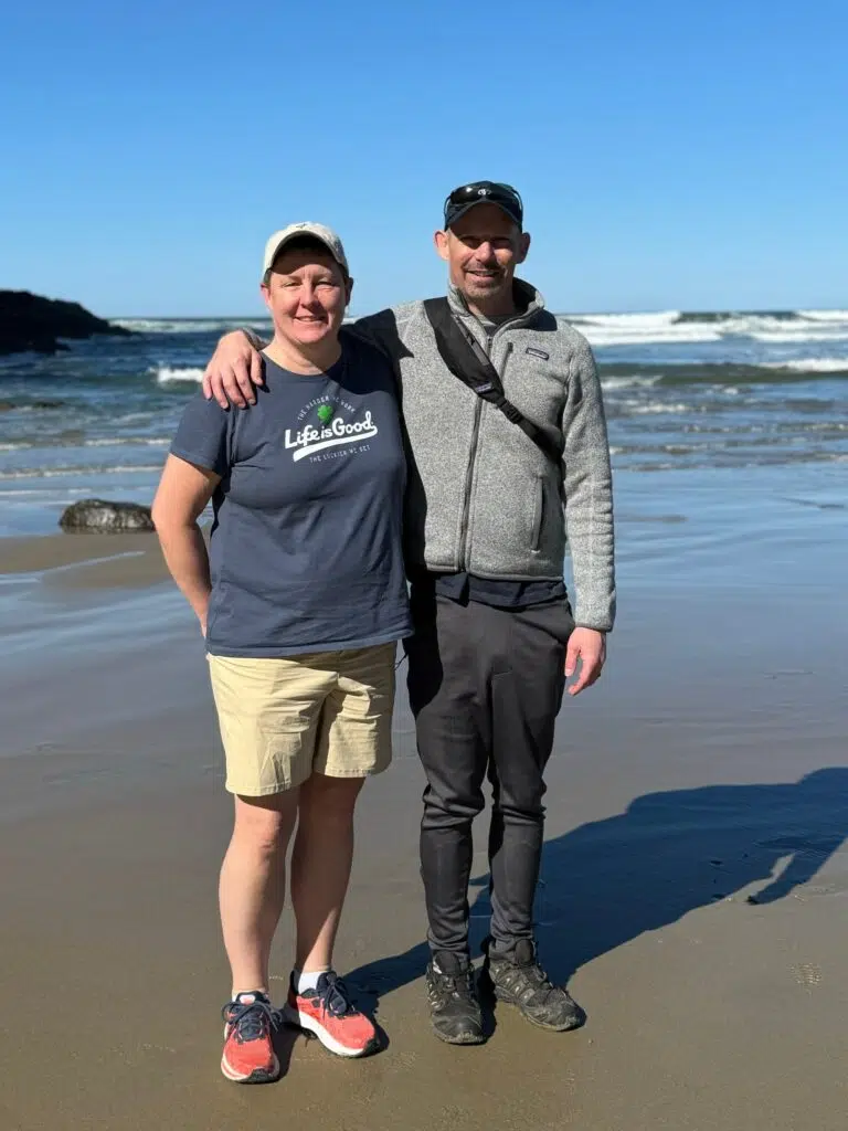 Mark Walter and I standing together on a sandy beach with ocean waves in the background.