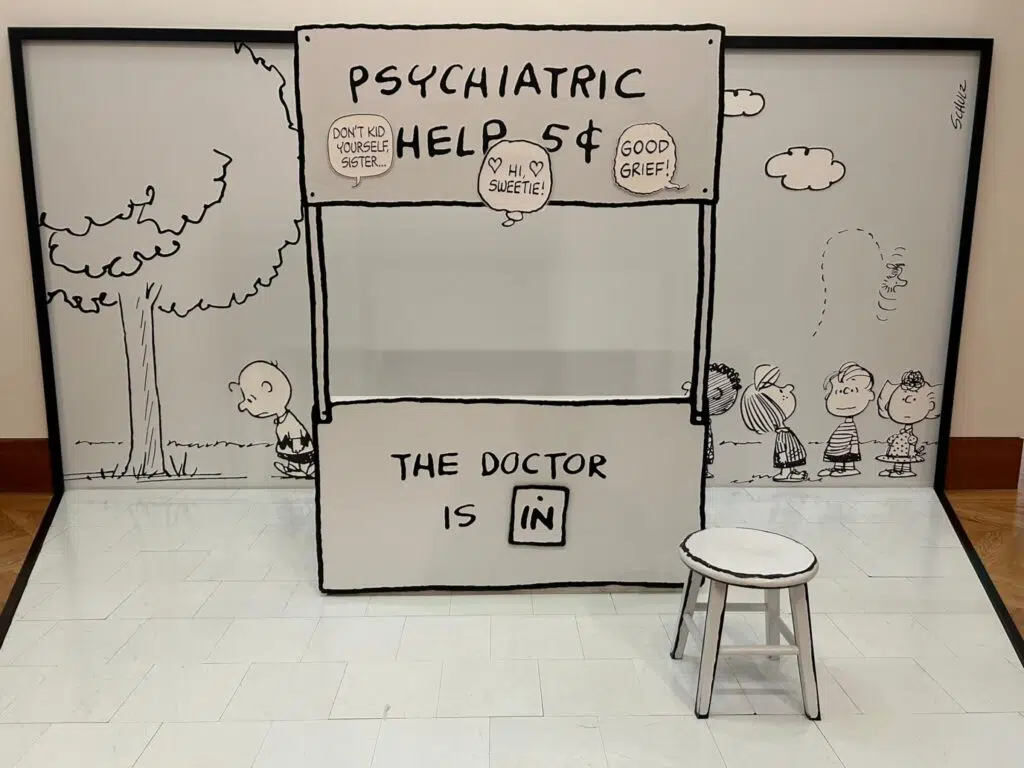 Life-size Peanuts comic display featuring Lucy's Psychiatric Help 5 Cents booth with Charlie Brown and other characters.
