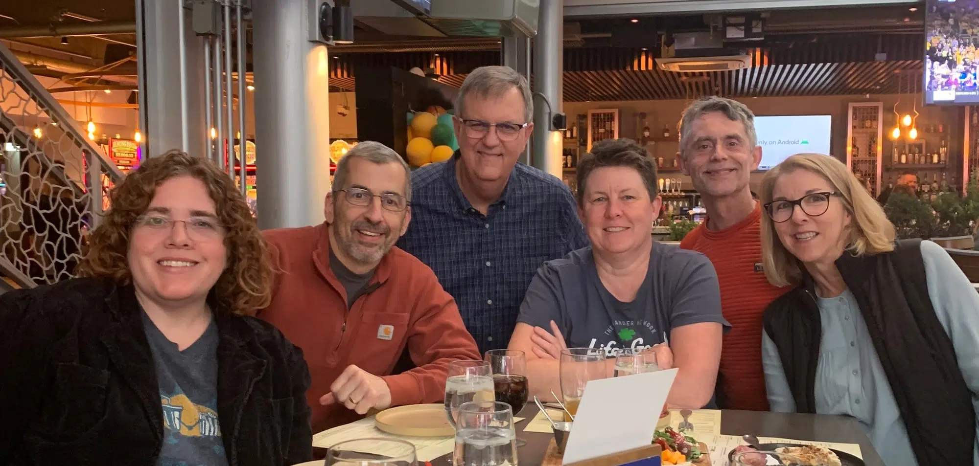 6 of the #SML gang at dinner, left to right: Christina Lanham with brown curly hair and glasses, wearing a grey t-shirt under a black jacket; Bob Kundrat, short grey hair and glasses, wearing a red half zip sweater; Jack Irby, short grey hair and glasses wearing a blue checked button down shirt, me with short brown hair wearing a blue t-shirt; Greg Kramer, short grey hair wearing a red t-shirt; Sheila Hart, blonde hair and glasses wearing a blue shirt under a black vest.