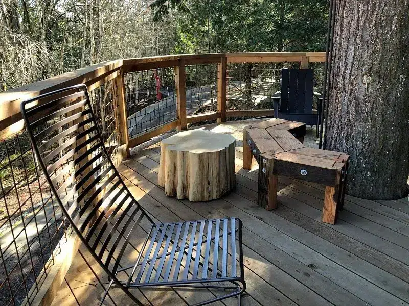 Wooden deck area at Microsoft Treehouse campus featuring metal bench seating, tree stump table, and forest surroundings