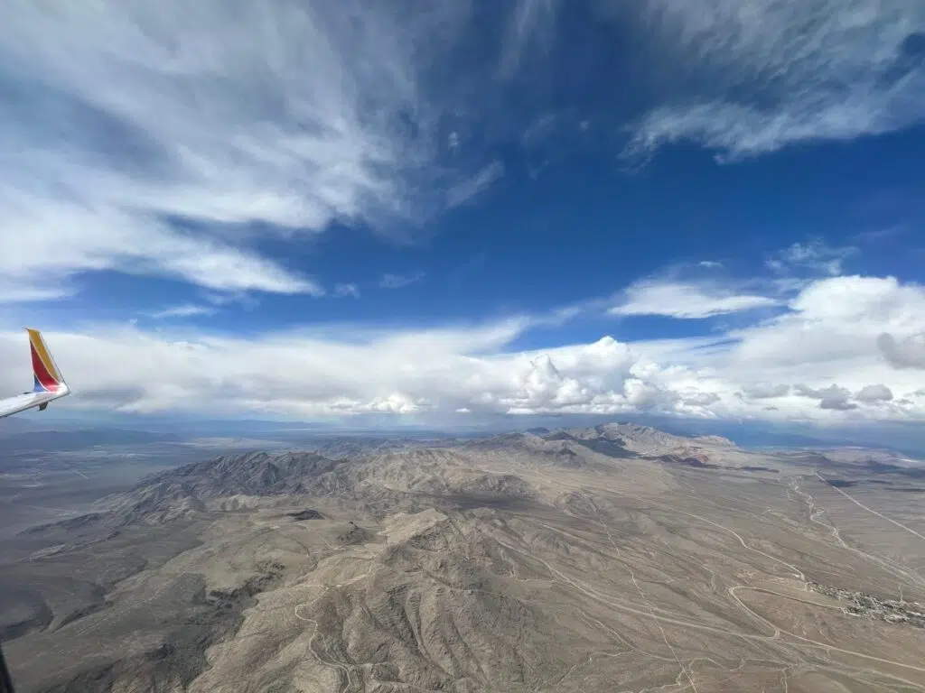Aerial view from Southwest Airlines plane showing desert mountain landscape and dramatic clouds approaching Las Vegas.